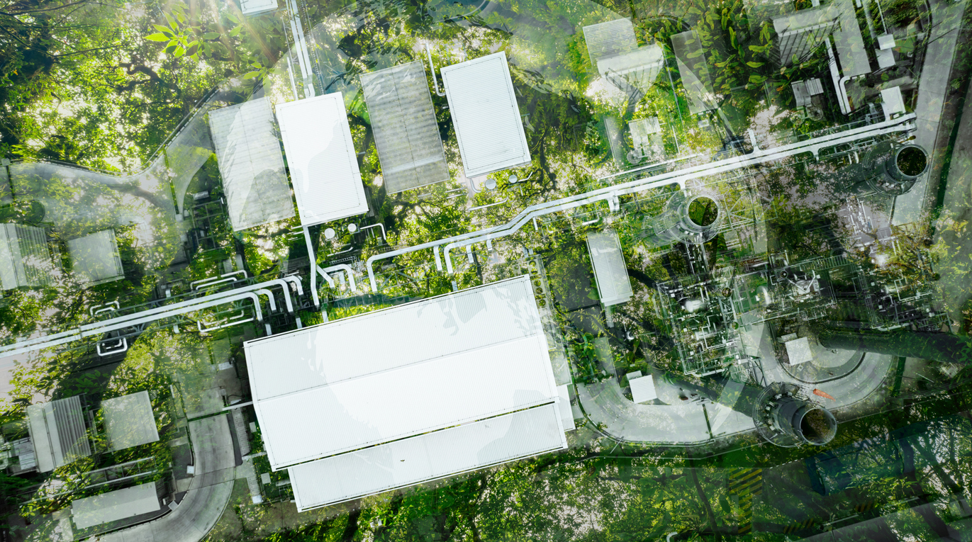 Aerial view factory roof amidst lush green tree forest. Sustainable practices for carbon reduction of factories. Sustainability in manufacturing. Carbon offsets and eco-friendly industrial practices.